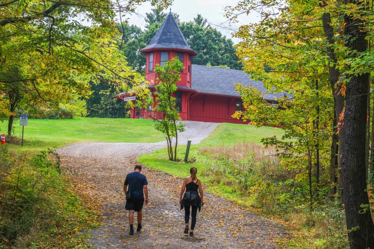 A man and a woman walk up a trail to a red building
