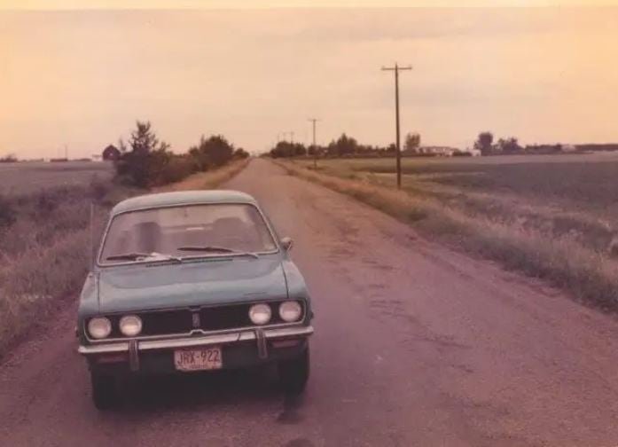 default-32777 A vintage photograph of a blue vehicle parked on the side of a rural road.